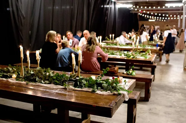 Head table dressed with greenery and roses under warehouse windows