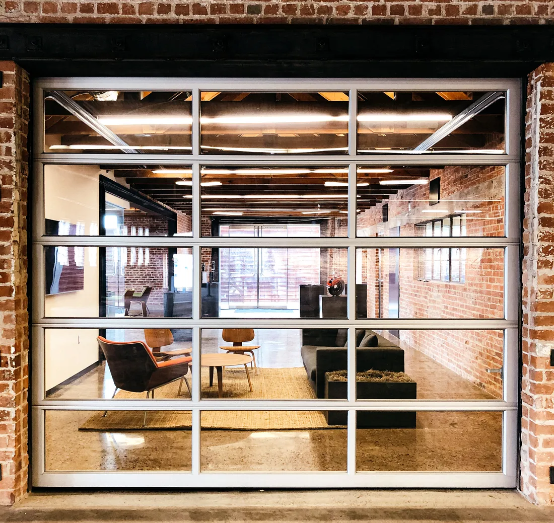 Restored lobby doorway framed in original red brick, golden afternoon light on the polished concrete floor